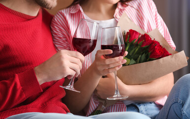 Happy young couple drinking wine at home on Valentine's Day