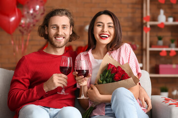 Happy young couple drinking wine at home on Valentine's Day