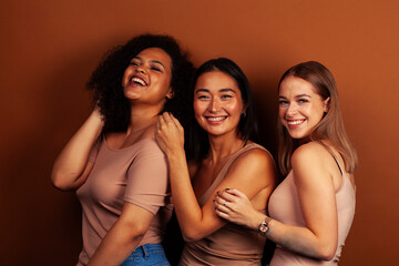 young pretty asian, caucasian, african woman posing cheerful together on brown background, lifestyle diverse nationality people concept