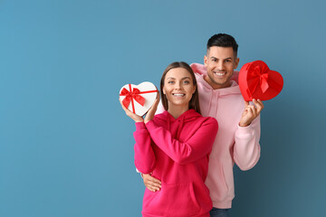 Happy young couple with gifts on blue background. Valentine's Day celebration