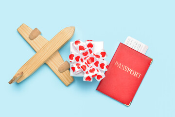 Wooden airplane with gift and passport on blue background. Valentine's Day celebration