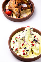 Chkmer chicken decorated with pomegranate on a light background