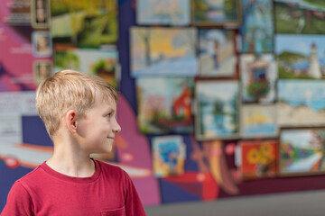In an art gallery of fine arts, the boy drew attention to the picture and looks at it with...