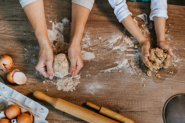 Top view of little girl with parent kneading dough