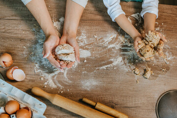 Top view of little girl with mother kneading dough from whole grain flour