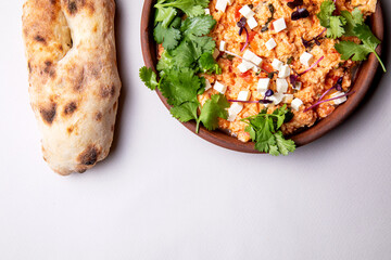 shakshuka with herbs, cheese and fresh pastries on a light background