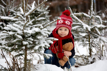 Cute toddler child in the park, standing between christmas trees