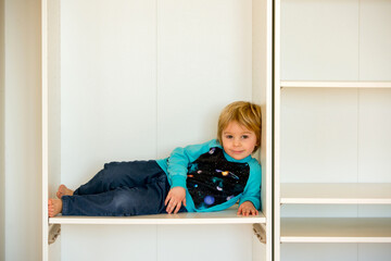 Cute child, sit in a white box in open wardrope