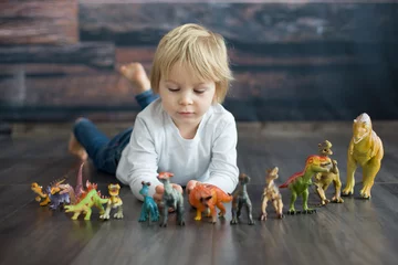 Foto auf Acrylglas Dinosaurier Blond toddler child, playing with dinosaurs at home
