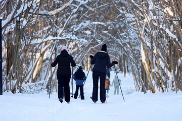 Fototapeta na wymiar People skiing, family leisure outdoors. Women and man skiers walking by snow in winter park