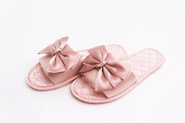 Close-up of pink satin female glamorous stylish home slippers with bows isolated on a white background 