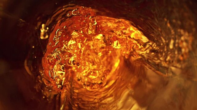 Super slow motion of pouring whiskey, rum or cognac inside the bottle, macro shot. Filmed on high speed cinema camera, 1000fps