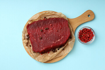 Obraz premium Concept of cooking with raw beef steak on blue background