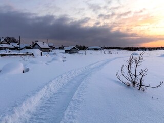 Winter landscape with a trail winding along the outskirts of the village in the snow.