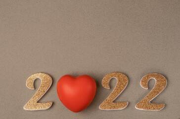 Number 2022 with a red rubber heart on a beige background. Copy space