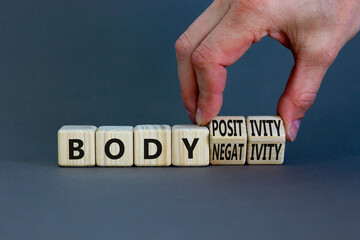 Body positivity or negativity symbol. Psychologist turns cubes, changes words body negativity to body positivity. Grey background, copy space. Psychological, body positive or negative concept.