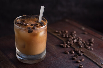 Vaso de café helado con canela y granos de café en una vieja maleta marrón	