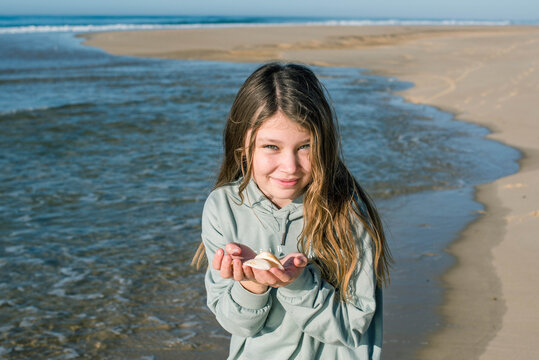 portrait of a pretty little girl with a radiant smile with seashells in her hands