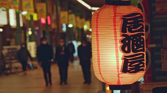 居酒屋の提灯と商店街を歩く人々