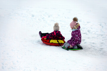 Children having fun on snow tubes. Winter entertainment, sledding and tubing in frosty day