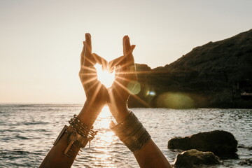 Middle aged well looking woman in white swimsuit and boho style braclets practicing outdoors on...