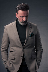 Obraz premium Portrait of a stylish elegant senior businessman with a beard and casual business clothes in photo studio isolated on dark background gesturing with hands