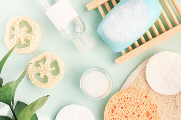 Obraz na płótnie Canvas Natural skincare cosmetic products top view light blue backround, facial cleasing soap foam toner bottle, hygiene eco sponges