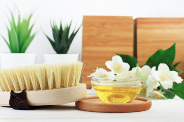 Fototapeta na wymiar Organic spa exfoliation, body care brush from natural sisal bristle and bowl of oil for skincare. Homemade body cleansing and beauty treatment with dry self massage and olive oil. Wooden, green, white