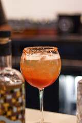 bartender preparing a red and yellow michelada glass at the bar counter