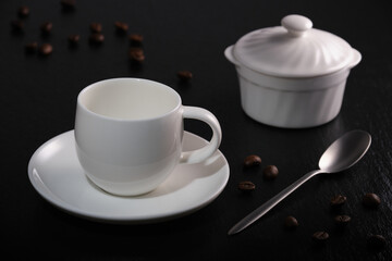 Obraz na płótnie Canvas White empty coffee cup on a black table. Coffee cup on a black background. Coffee beans on black. Breakfast coffee on a black background.