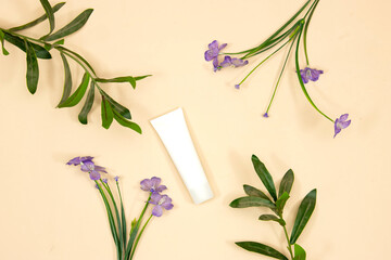 Beauty cosmetics tube; branding mock up isolated on pink background. Package for hand cream or scrub. Beauty cosmetics tube, branding mock up with purple flowers