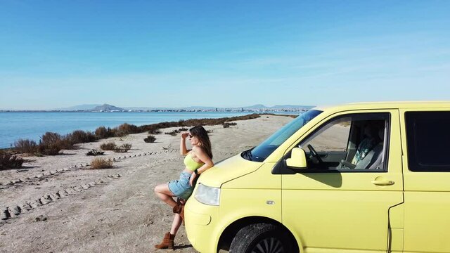 yellow camper van arrives at the beach in front of the sea during a summer trip - girl alone traveling goes down and looks at the sea - view from the drone in Murcia Spain Mar minor 
