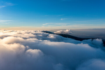 Thick layer of white clouds above mountains at sunrise