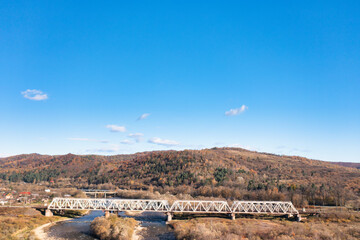 Long railroad bridge over river leading to valley settlement