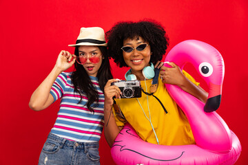 Happy smiling african woman holding flamingo rubber ring and enjoying their summer vacation .Young African American woman isolated on colour red background in vacation with travel .
