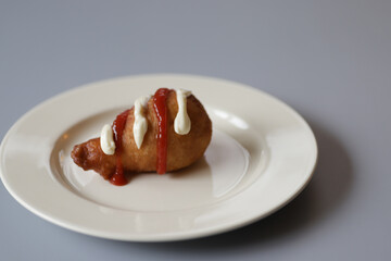 Fried donut in the form of chicken leg with mayonnaise and ketchup.