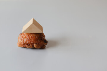 Fried donut with toy wooden roof like house.