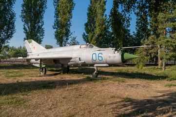 Supersonic aircraft MIG 21. Combat fighter installed in the Victory Park of Nizhny Novgorod on the ground, surrounded by trees and against the sky. High quality photo
