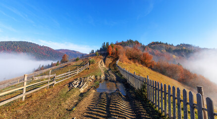 The dirt road is fenced with an old wooden fence. morning mountain landscape.