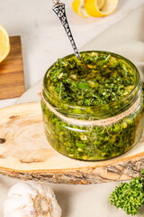 Large jar of chimichurri sauce on a wooden board.