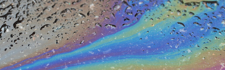 Multicolored stains from petroleum products on wet asphalt.