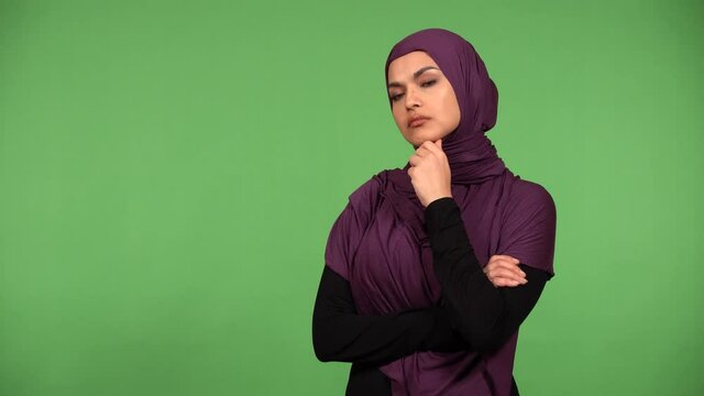 A young beautiful Muslim woman thinks about something - green screen background