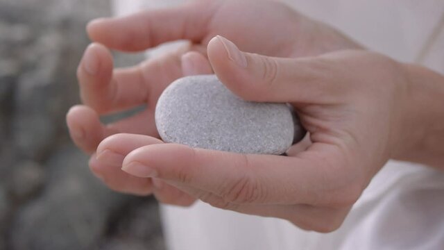 Woman plays with stone rolling the stone from palm to palm. Close-up.
