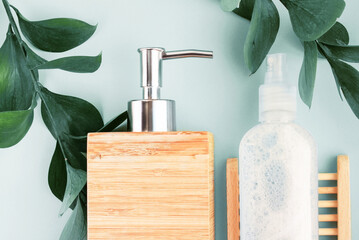 Natural skin care products top view blue background green plant leaves. Wooden soap dispenser and...
