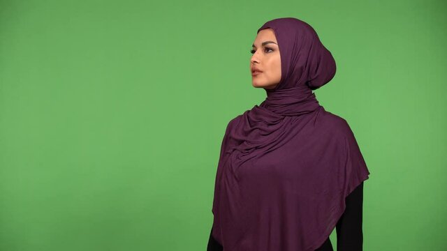 A young beautiful Muslim woman looks around in awe - green screen background