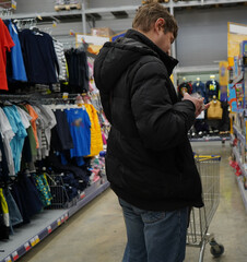 Fototapeta premium A man is shopping in a supermarket. Preparing for the big holidays in the store. daily list of products and products.