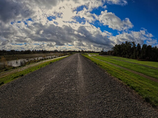 Fototapeta na wymiar wide angle view of a levee gravel road on a cloudy day