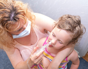 A young woman cleans her nose from snot to a small child, a girl of 4 years old.