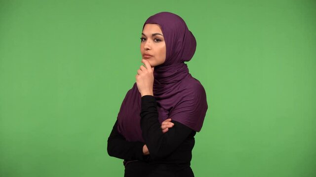 A young beautiful Muslim woman thinks about something - green screen background
