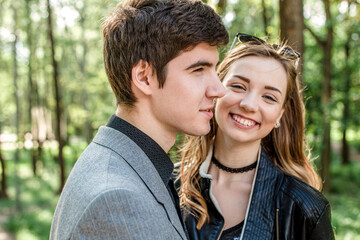 Fototapeta premium laughing happy girl in arms of loving guy. handsome young guy in park on a walk with a friend in spring.